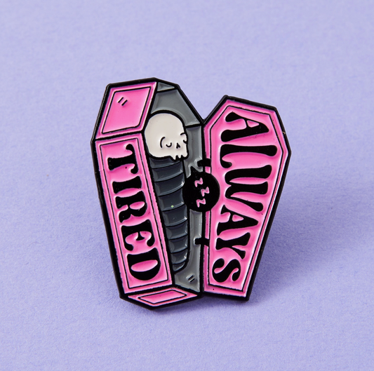 a pink and black pin with a skull inside of it